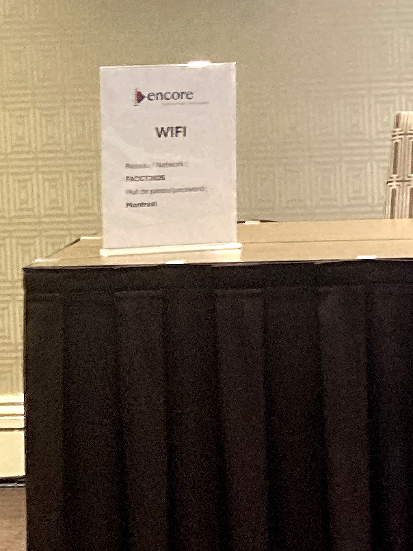 A conference Wi-Fi sign, photographed from a distance and slightly out of focus, showing the network FACCT2026 and the password Montreal.